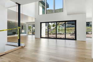 Spacious interior featuring light wood-finish flooring, high ceilings, and a wall of multi-panel sliding glass doors