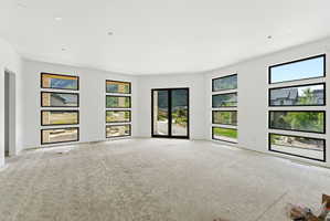 Spacious room featuring multiple horizontal windows with black framing, a full-light patio door, recessed ceiling lighting, and a neutral wall palette
