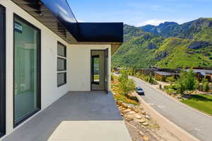 Outdoor patio featuring large format tile flooring, black trim windows, a modern black soffit, and an open doorway