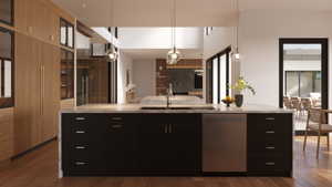 Kitchen island featuring a stainless steel sink, integrated dishwasher, and light-toned countertop