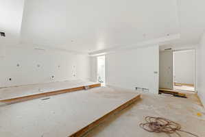 Expansive interior space featuring a recessed ceiling, white painted walls, and an elevated platform structure