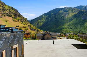 Mountainous landscape surrounding a residential area, featuring a concrete pad with visible construction materials