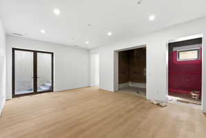 Open concept room featuring recessed lighting, light wood-finish flooring, and a double-door exterior entry with an integrated staircase