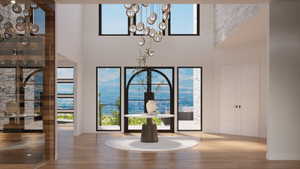 Two-story foyer featuring hardwood flooring, a contemporary chandelier, tall windows with mountain and city backdrops, and a pair of panel doors