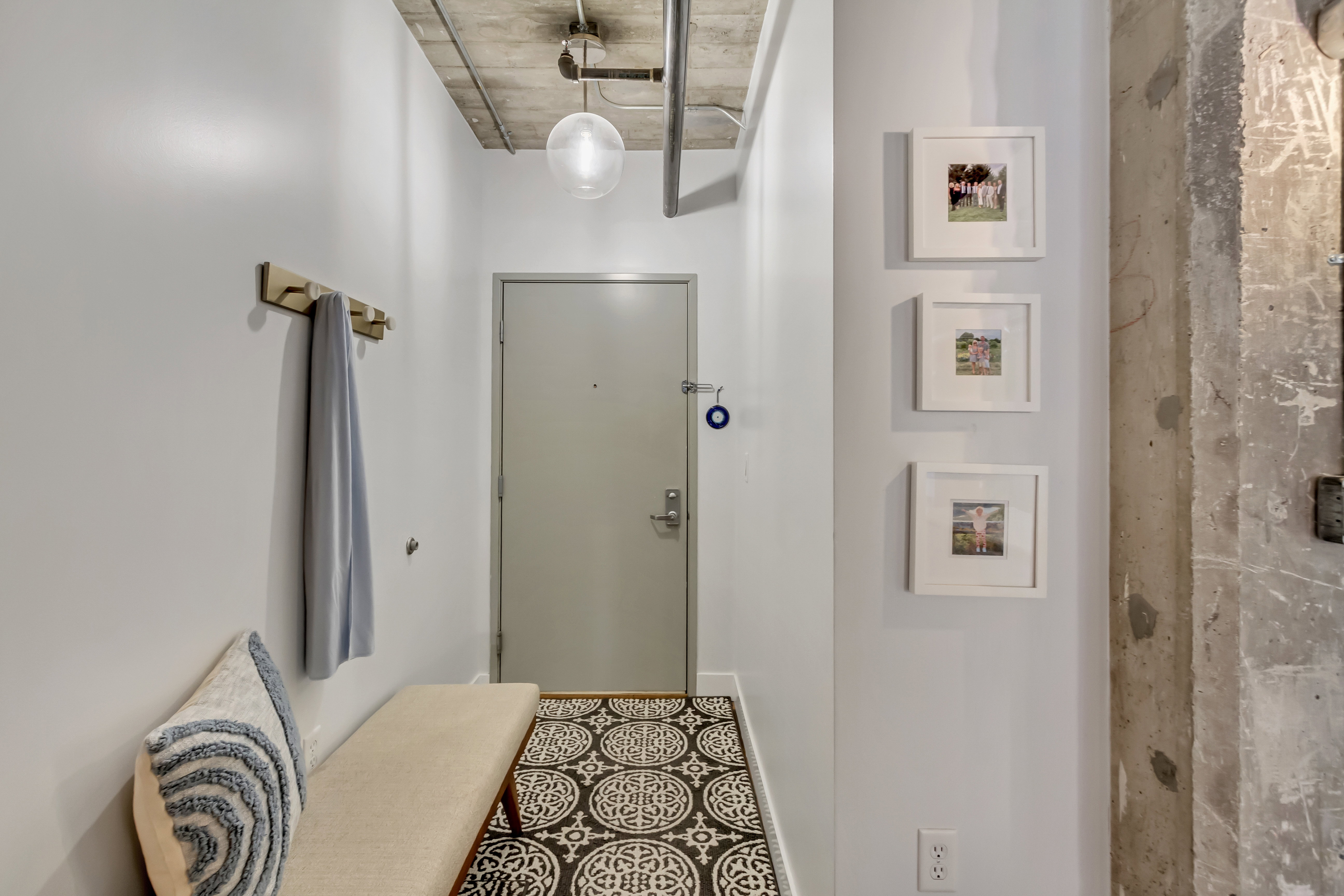 Entryway featuring a patterned floor tile, exposed concrete ceiling with industrial piping, a flush-mounted spherical light fixture, and a solid entry door