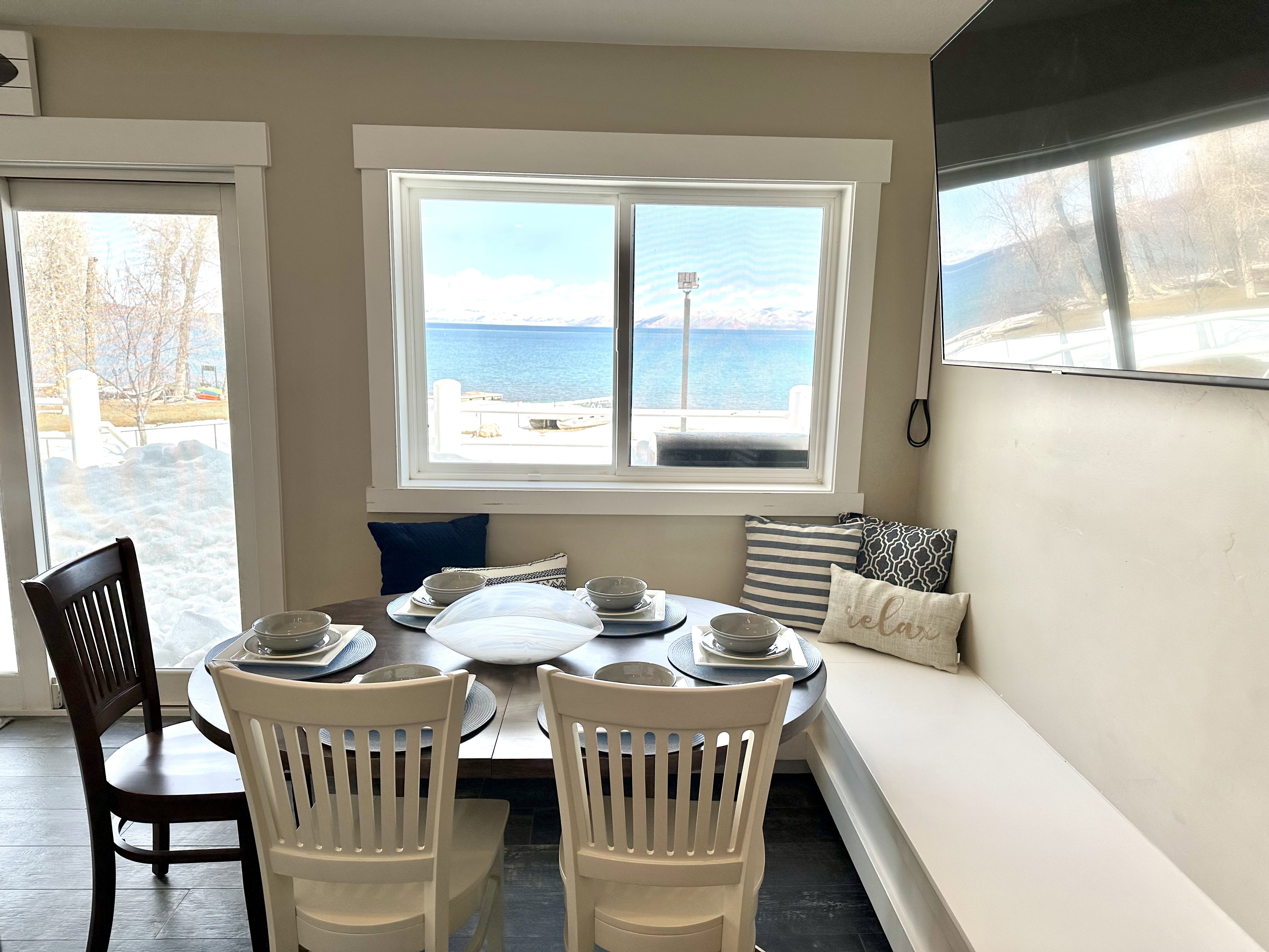 Dining nook featuring a built-in bench, dark tile flooring, and a large window overlooking a body of water with distant mountains