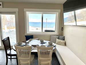 Dining nook featuring a built-in bench, dark tile flooring, and a large window overlooking a body of water with distant mountains