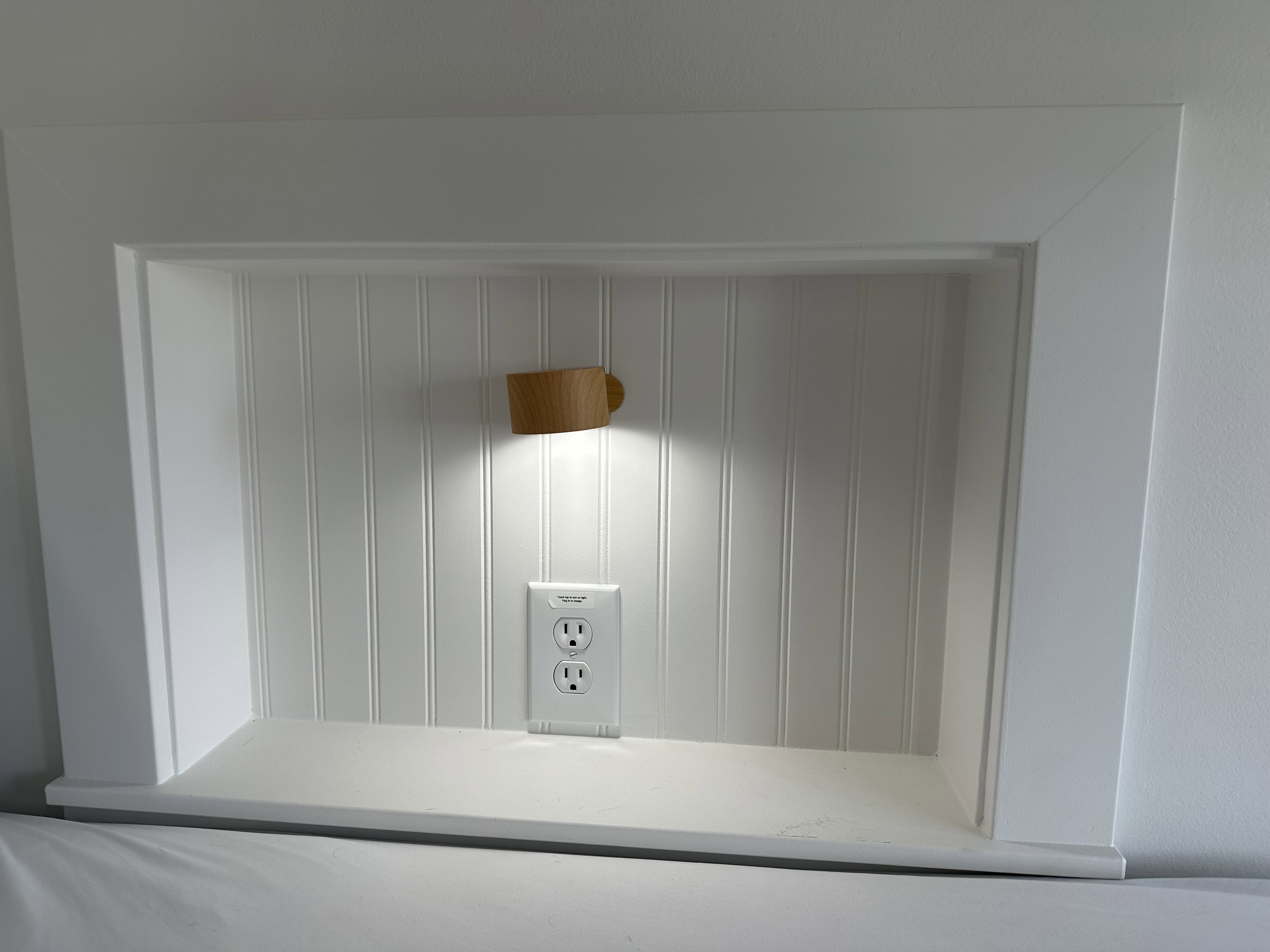 Built-in wall niche with beadboard backing, integrated lighting, and a power outlet