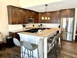 Contemporary kitchen featuring rich wood cabinetry, stainless steel appliances, a white tile backsplash, and wood-finish flooring