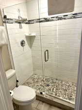 Walk-in shower with clear glass enclosure and pebble-tiled floor