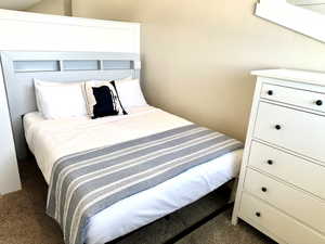 Carpeted bedroom area featuring light beige wall paint and a white built-in headboard