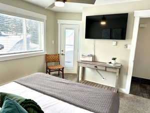 Bedroom featuring a ceiling fan with integrated lighting, a large window with blinds, a glass-paneled door, and carpet flooring