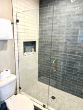 Enclosed shower with clear glass paneling and a brushed nickel handle