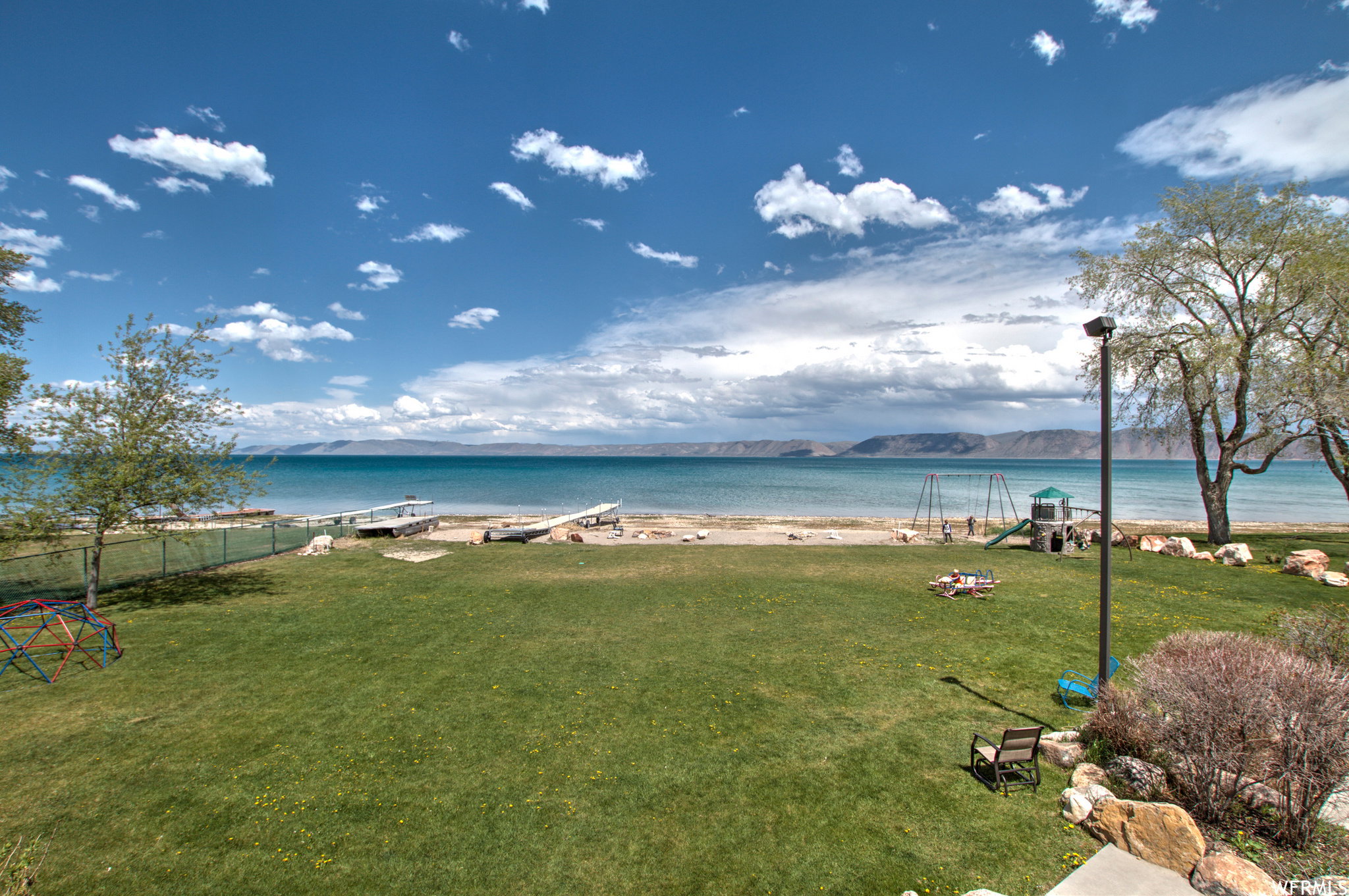 Expansive green lawn extending to a sandy shoreline with direct water access