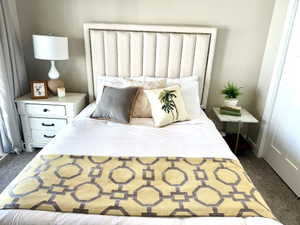 Upholstered channel-tufted headboard with nailhead trim, neutral wall color, and carpet flooring