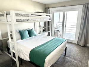 Room featuring a white metal bunk bed, neutral carpeting, and a white sliding glass door