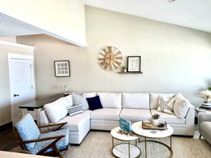 Vaulted ceilings above a spacious living area featuring a large sectional sofa and wood-finish flooring