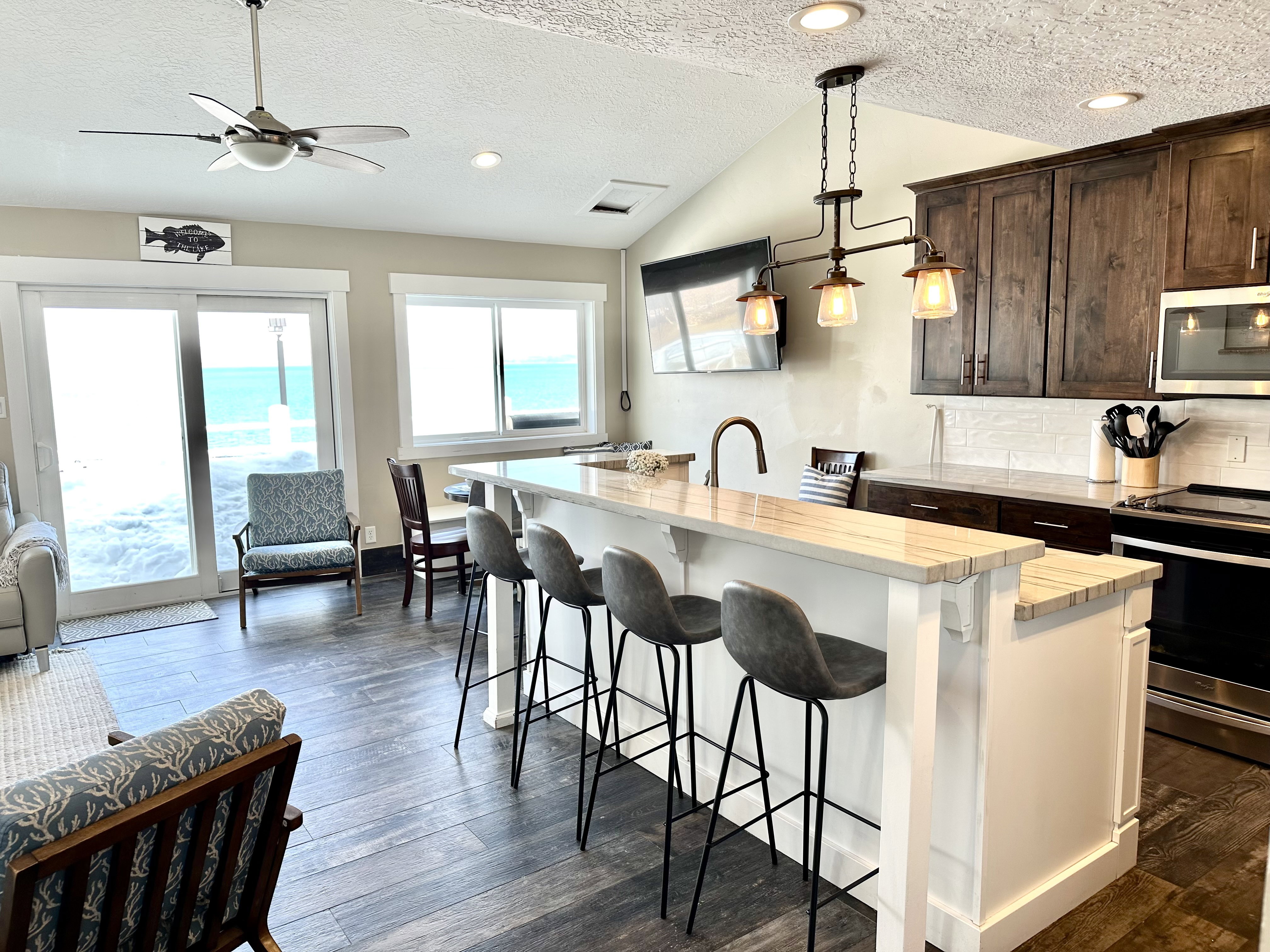 Open-concept common area featuring wood-finish flooring, a vaulted ceiling, and a kitchen island with seating