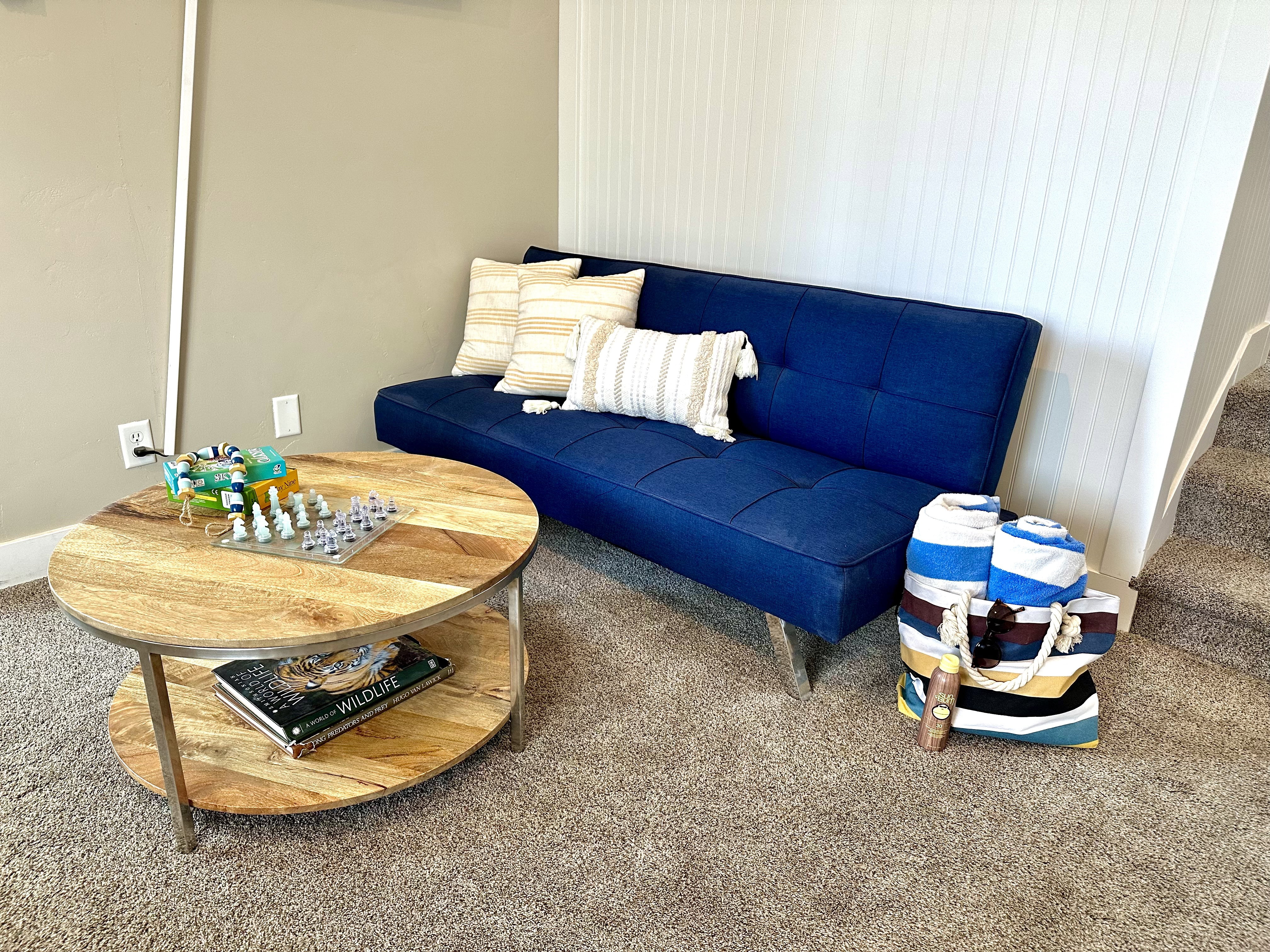 Carpeted room featuring a two-tier round wood-finish coffee table with metal legs and a white beadboard accent wall
