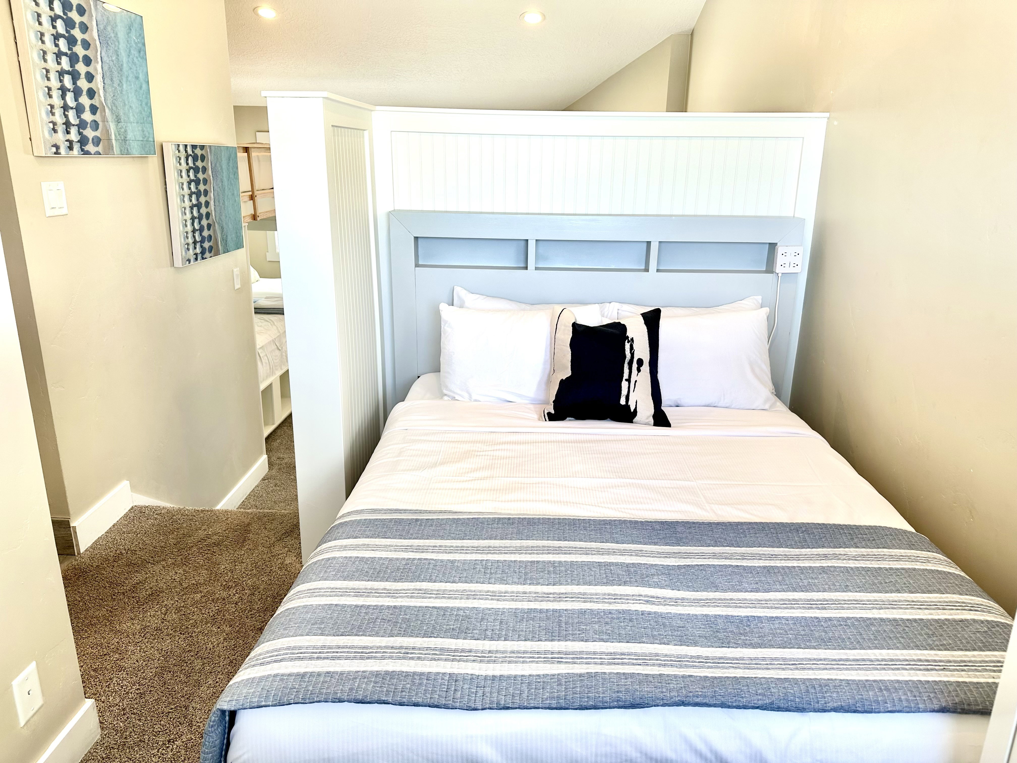 Integrated bed frame with built-in headboard featuring beadboard paneling and shelving