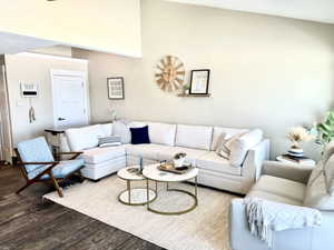 Living area featuring vaulted ceilings, wood-finish flooring, and a large area rug