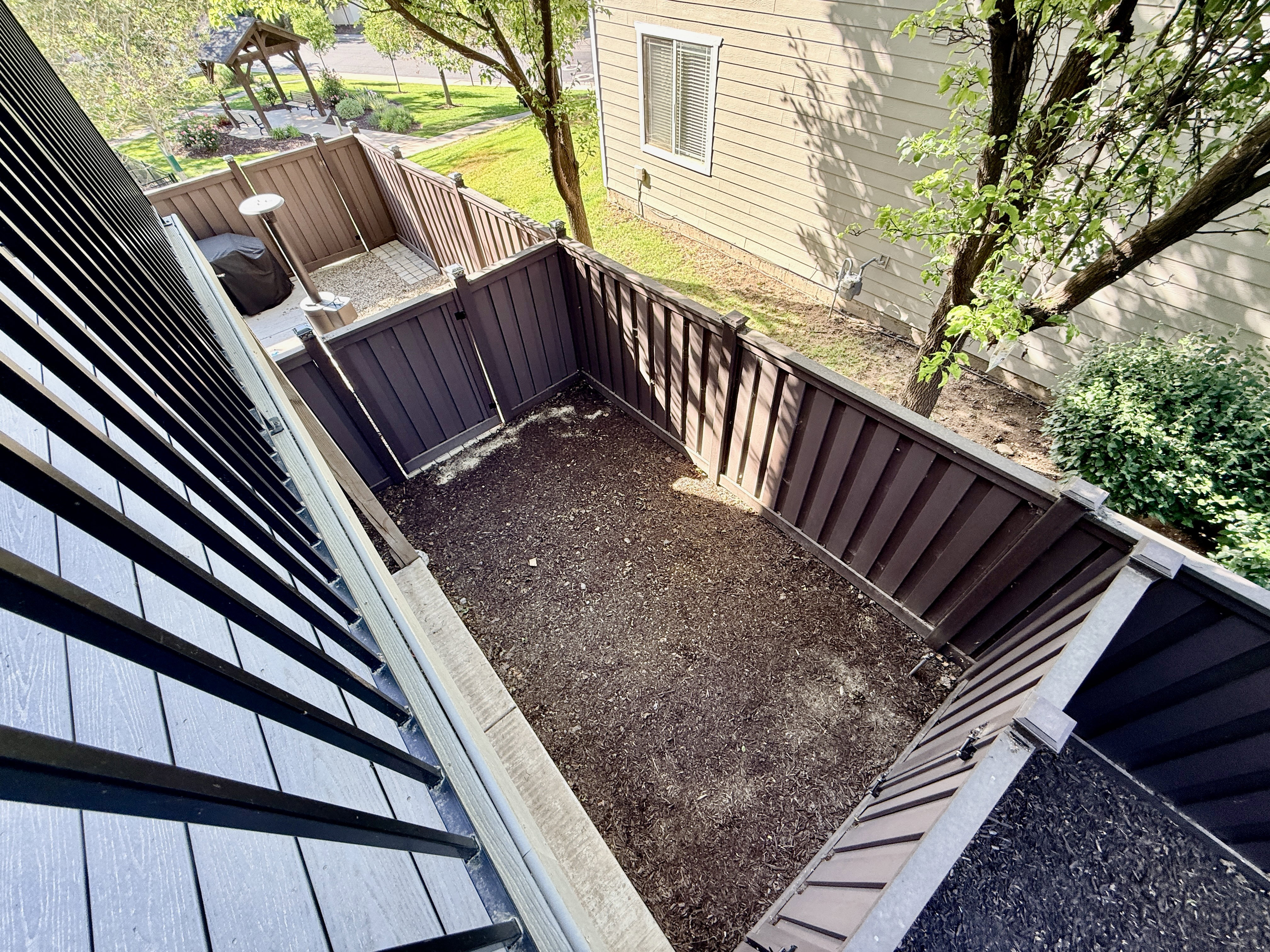 Private fenced outdoor space featuring a soil bed