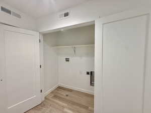 Dedicated laundry area featuring wood-finish flooring, white walls, and a built-in shelf