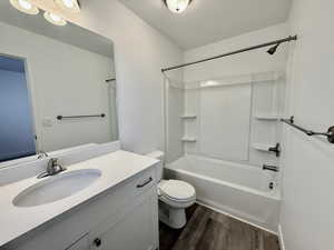 Bathroom featuring a white vanity with an integrated sink, a rectangular mirror, and a white tub/shower combination with built-in shelving