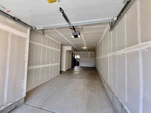 Garage interior featuring a concrete floor, unpainted drywall walls, and an overhead garage door opener