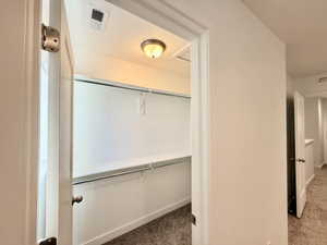 Walk-in closet featuring white walls, integrated shelving, and dual hanging rods