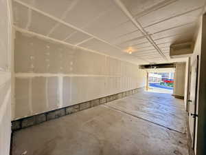 Spacious garage with unfinished drywall, concrete flooring, exposed ceiling joists, and an overhead garage door opener