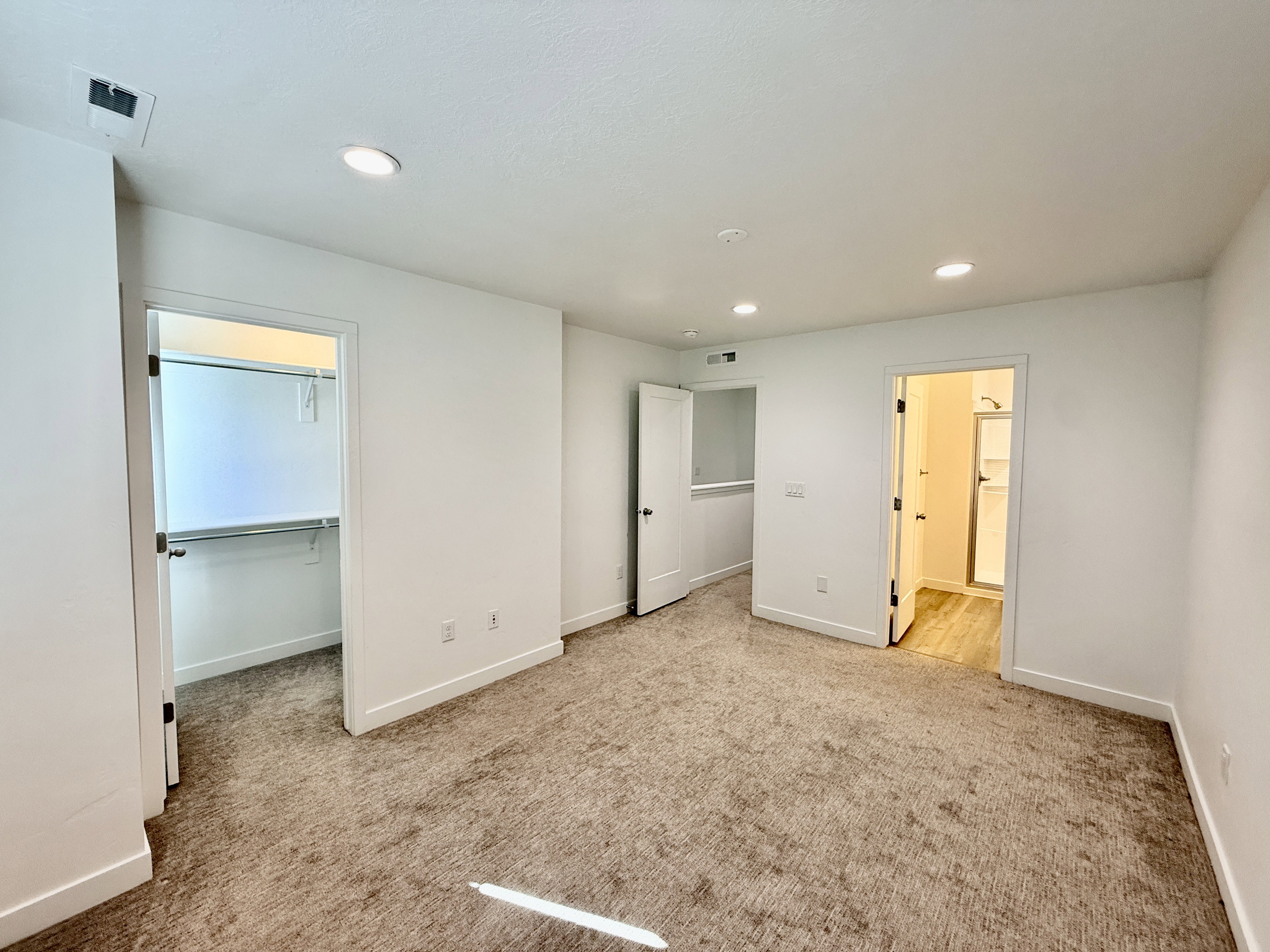 Spacious room featuring neutral carpeting, recessed lighting, white walls, and bright baseboards