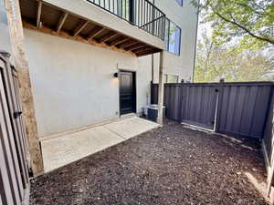 Private fenced patio space featuring a concrete pad and dark mulch ground cover