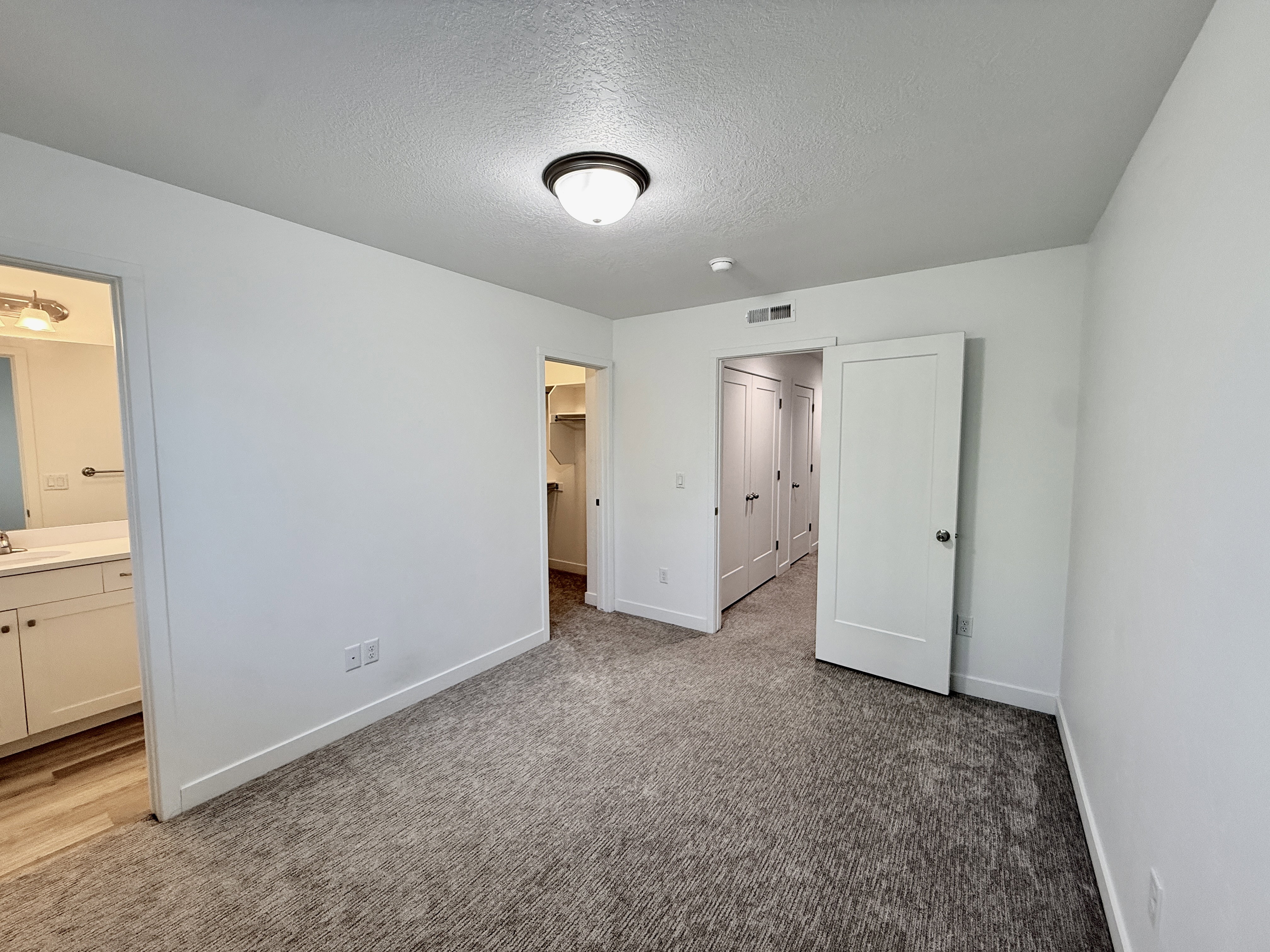 Spacious room featuring neutral carpeting, white walls, and a semi-flush mount ceiling light