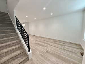 Open-concept living area featuring light wood-finish flooring, recessed ceiling lighting, and crisp white walls