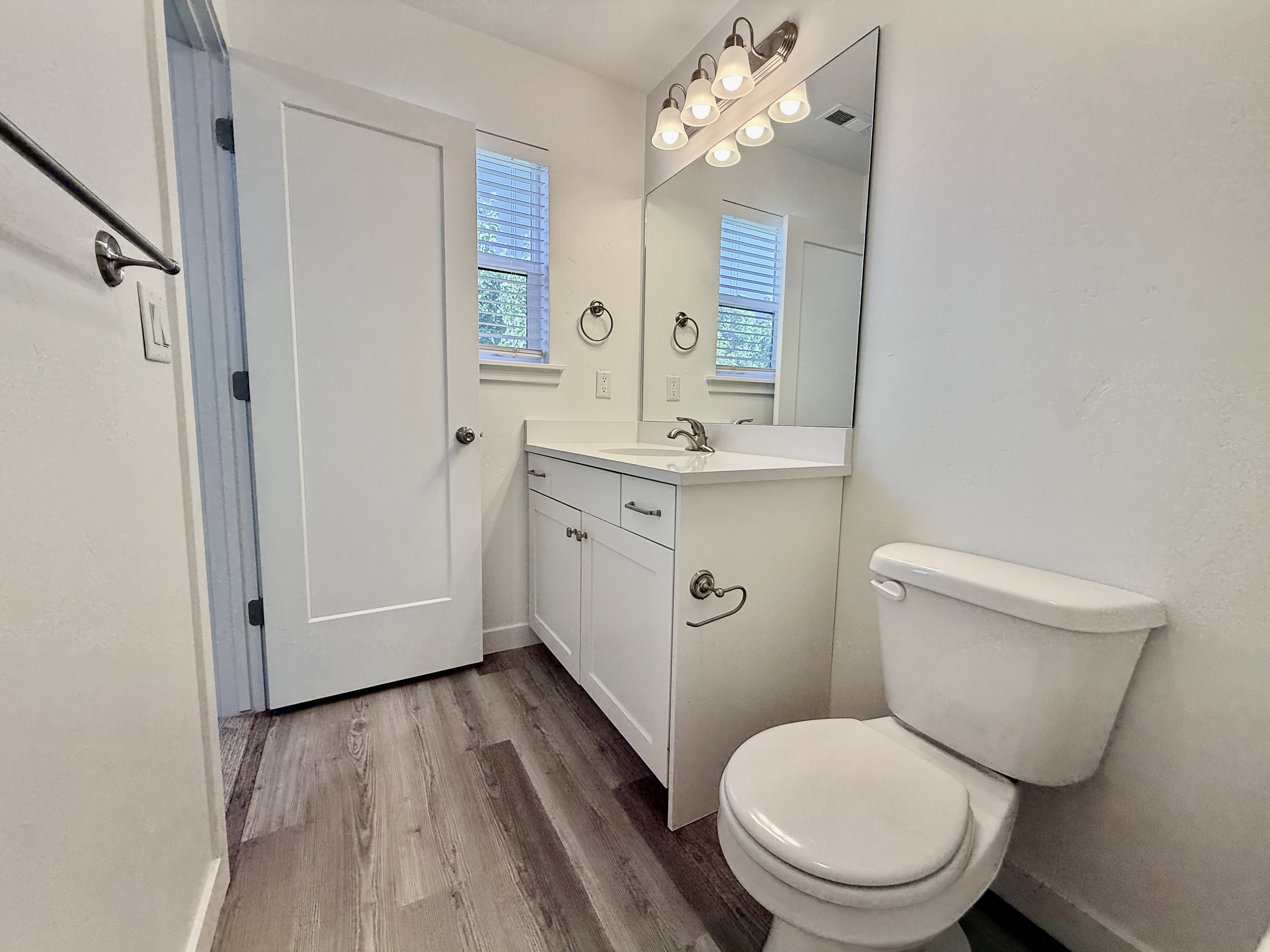 Bathroom featuring a white vanity with integrated sink, a rectangular mirror, and a wall-mounted light fixture