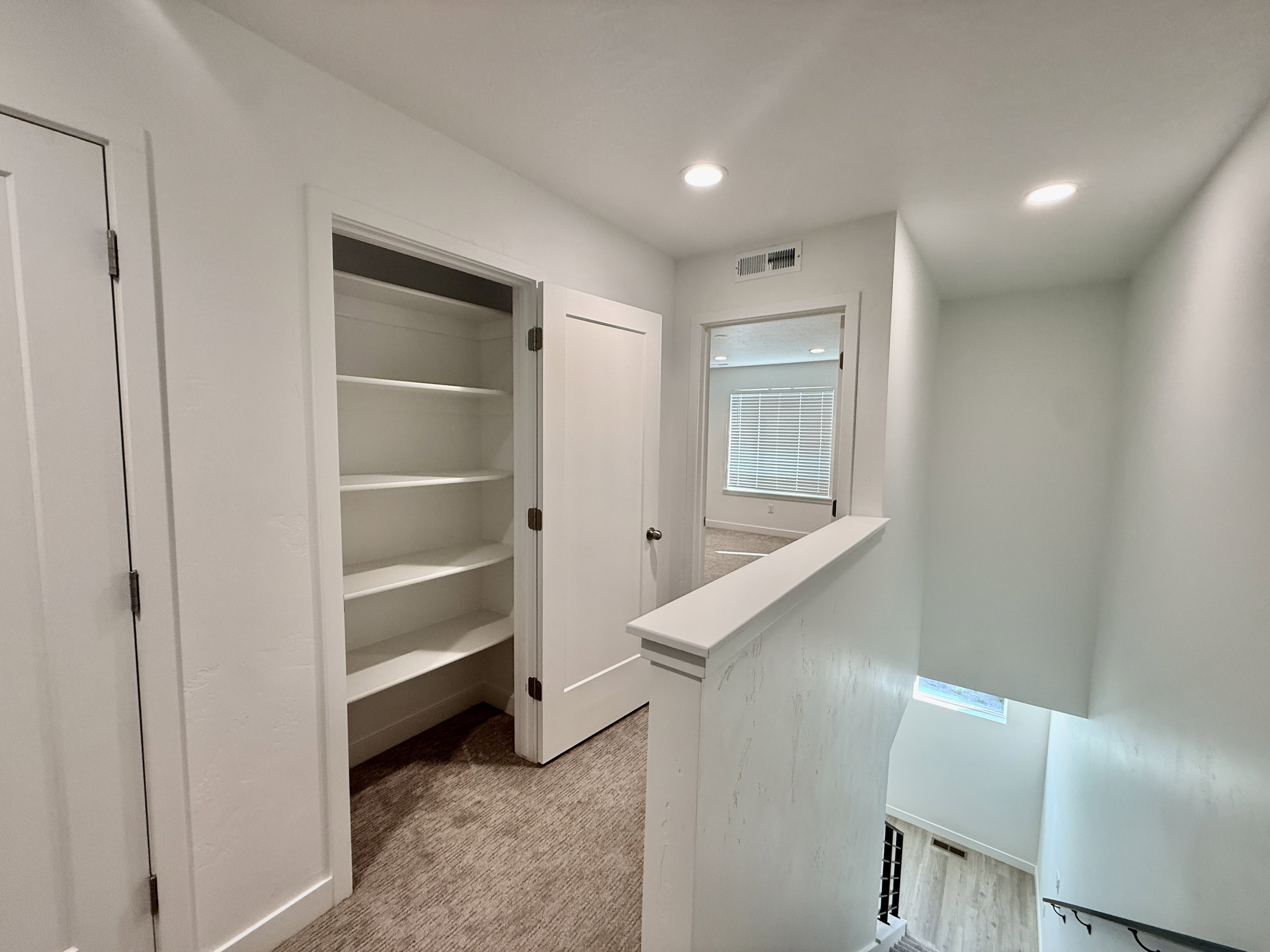 Upper-level hallway featuring a built-in shelving unit, neutral wall paint, recessed lighting, and carpeted flooring