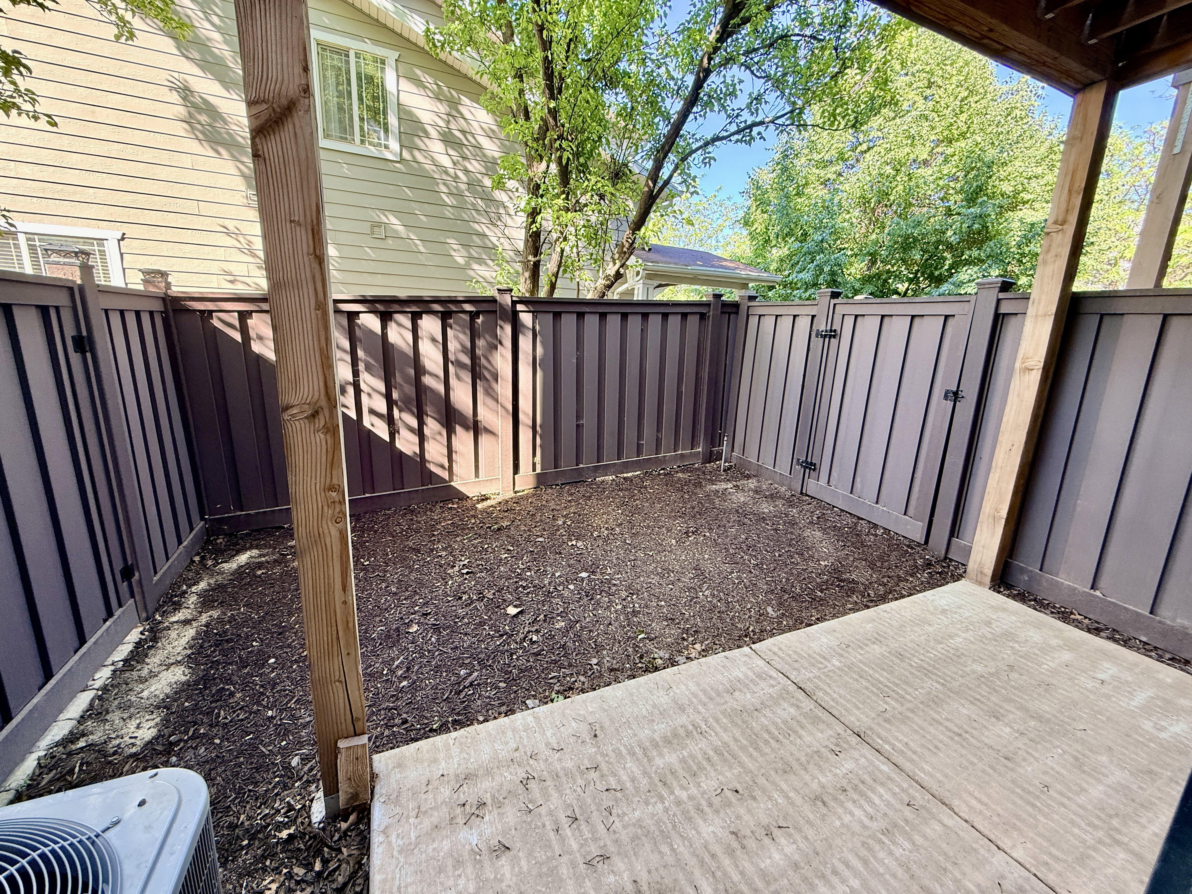 Private fenced patio featuring a concrete surface and a landscaped planting area