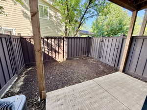 Private fenced patio featuring a concrete surface and a landscaped planting area