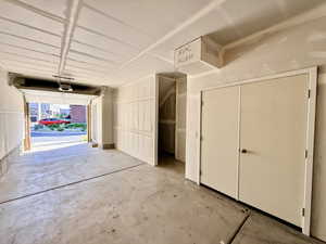 Spacious garage featuring a concrete floor, exposed ceiling joists, and a garage door opener system