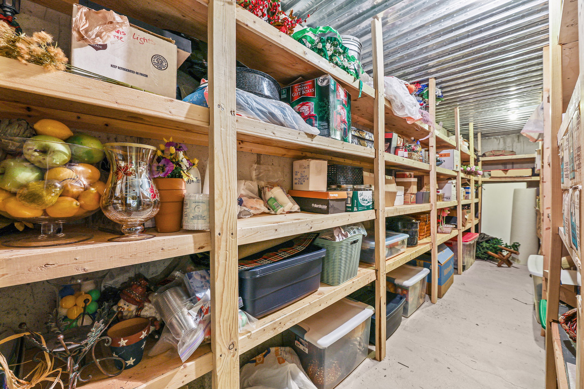 Utility room with extensive built-in wooden shelving, a concrete floor, and corrugated metal ceiling