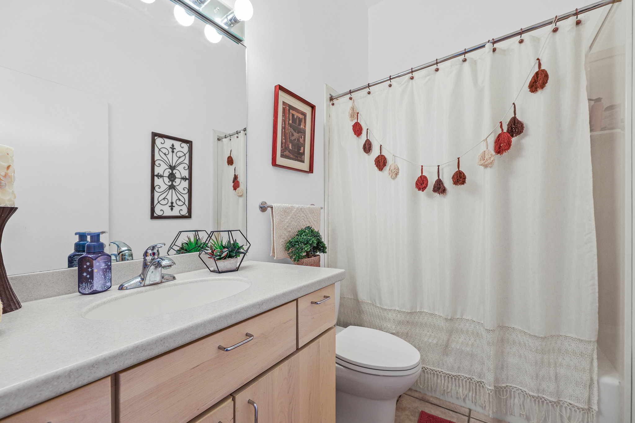 Bathroom featuring a light-toned wood-finish vanity with a light countertop and integrated sink, a chrome faucet, and a large mirror