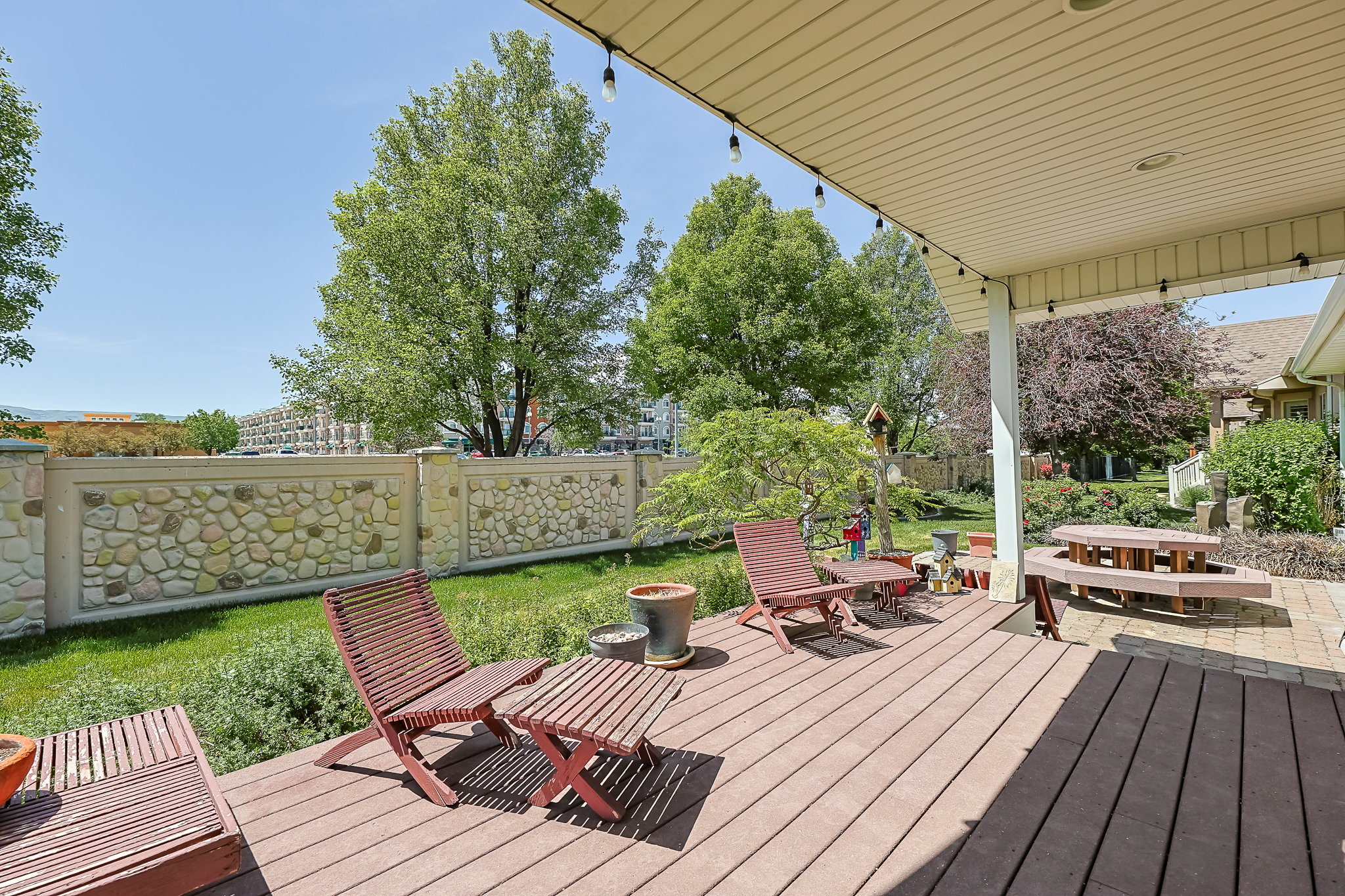 Covered patio featuring composite decking, exposed ceiling rafters, and string lighting