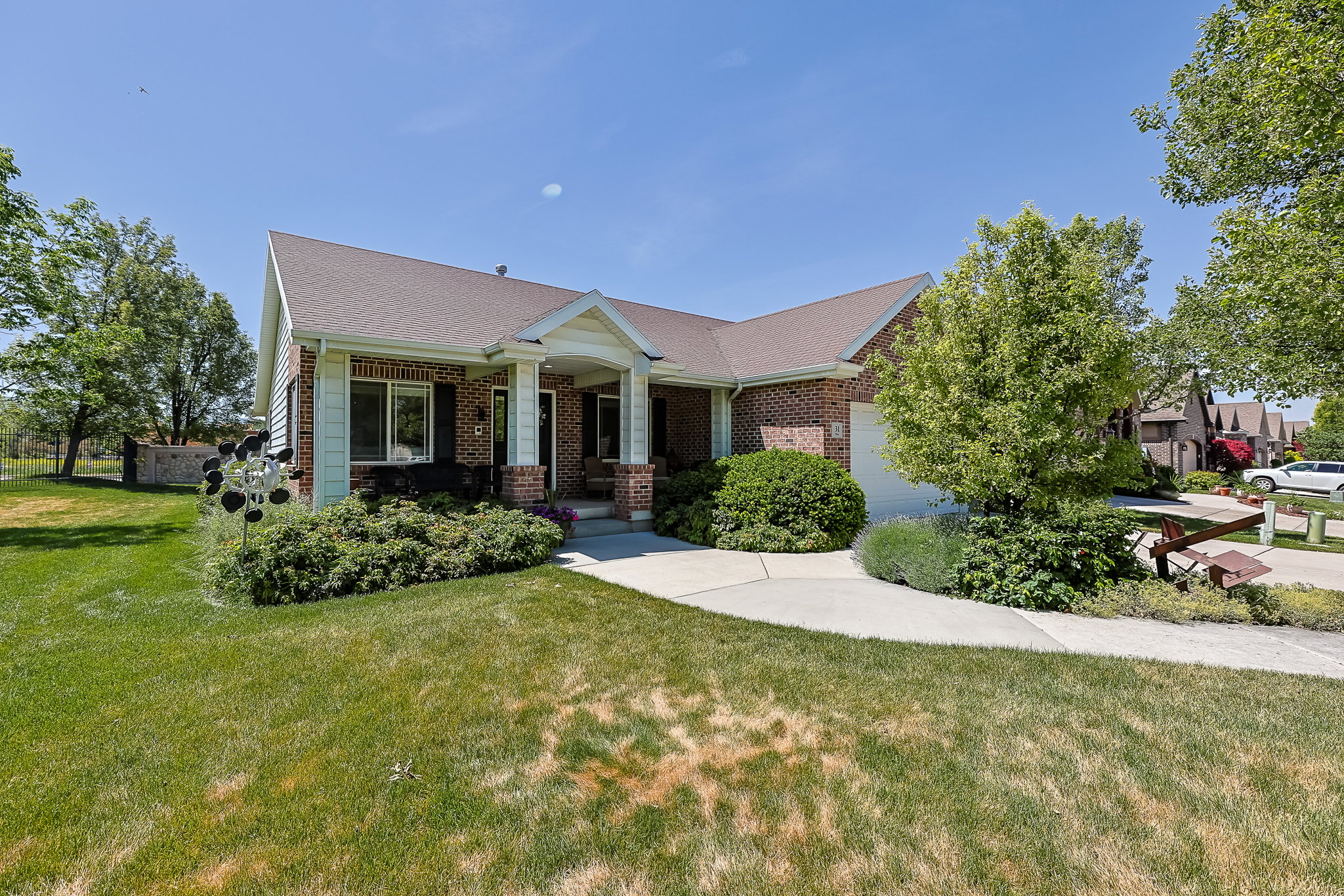 Brick and siding exterior featuring a covered entry, attached garage, and mature landscaping