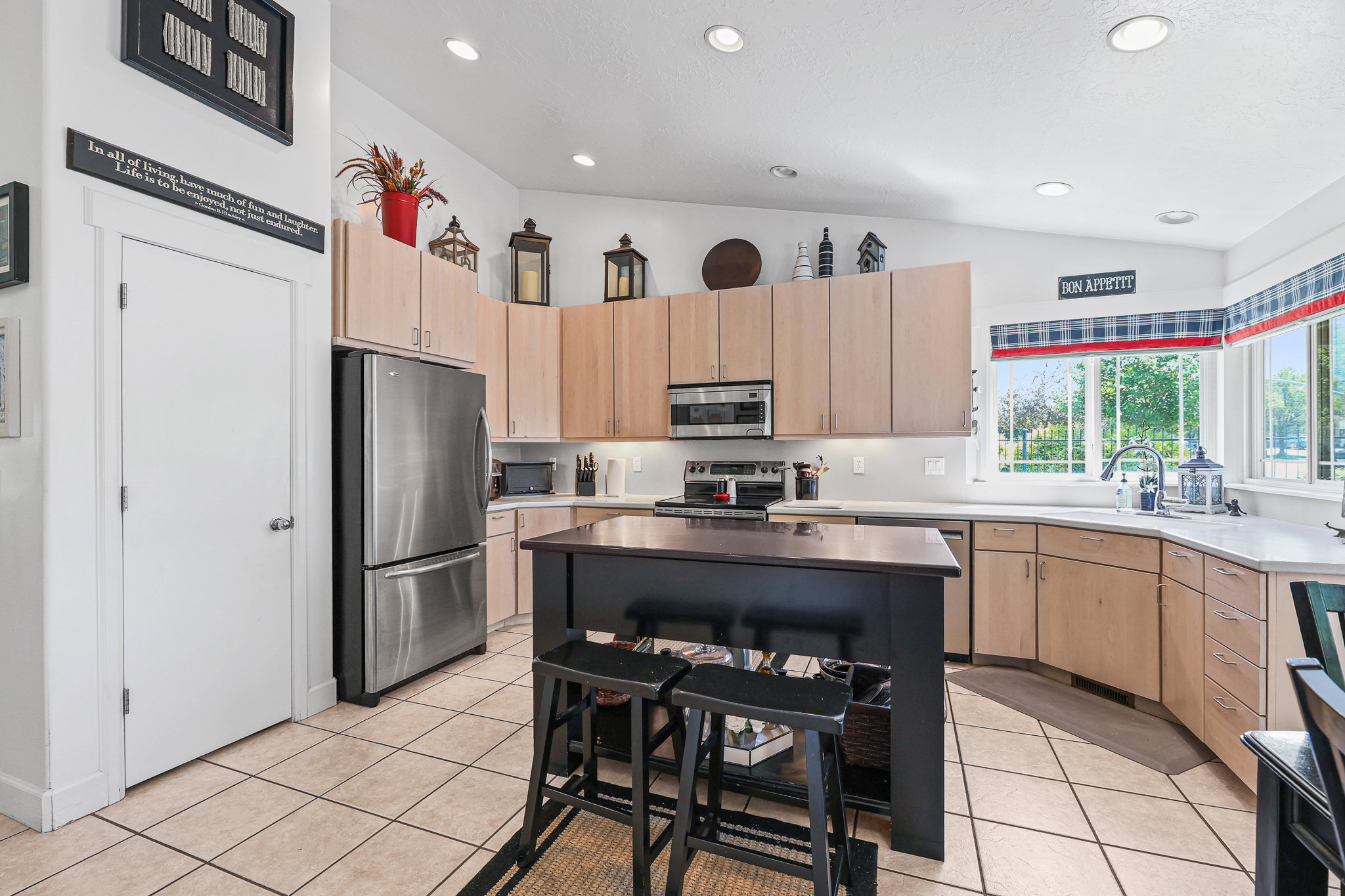 Spacious kitchen featuring an island with seating, stainless steel appliances, light-toned cabinetry, light countertops, and tile flooring