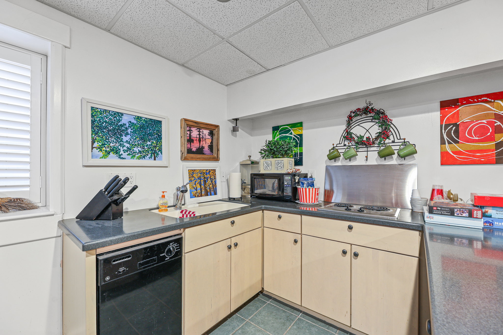 Corner kitchen area featuring light wood-finish cabinetry and dark countertops