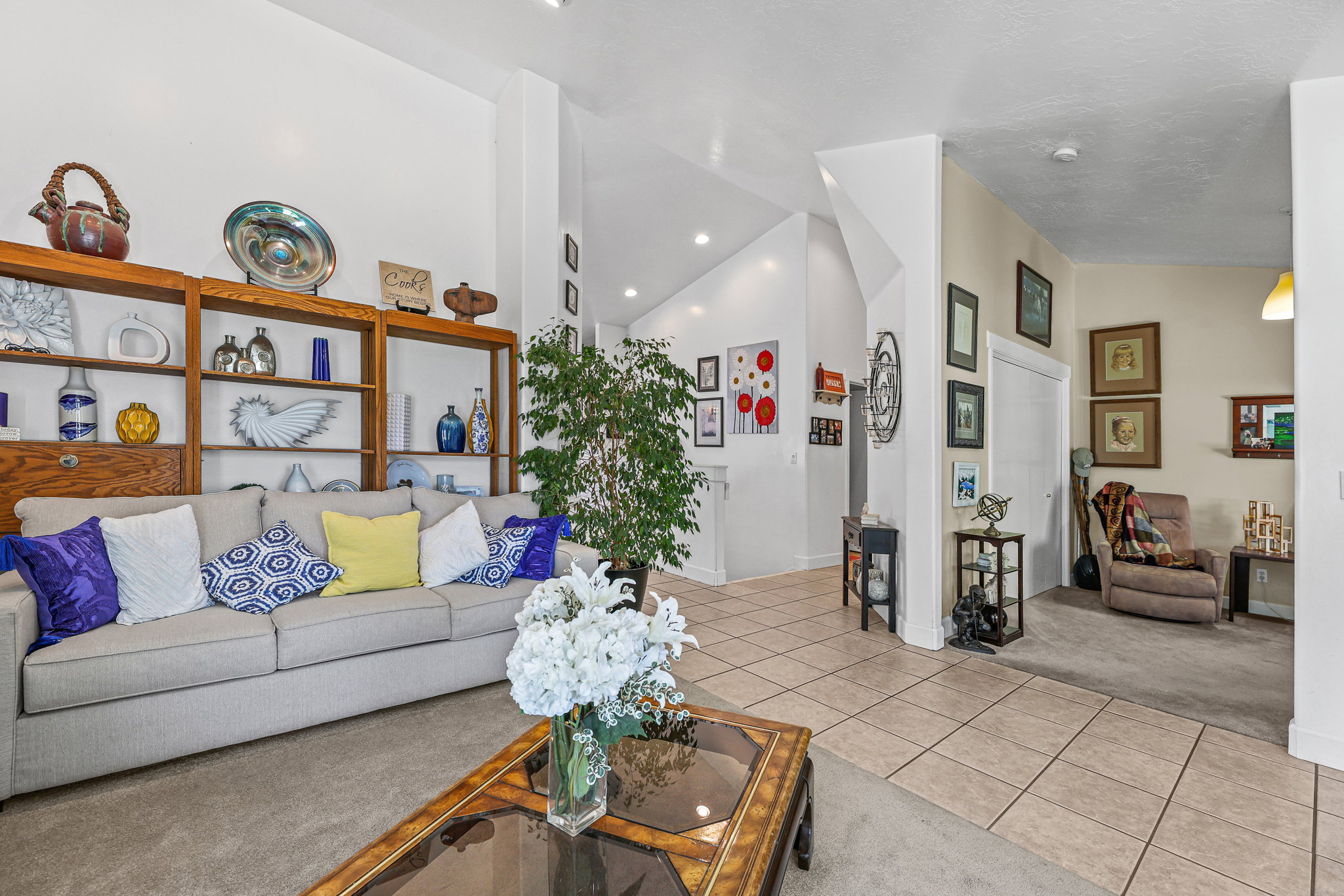 Spacious living area featuring high vaulted ceilings, integrated shelving with lower cabinetry, and a combination of carpet and large format tile flooring