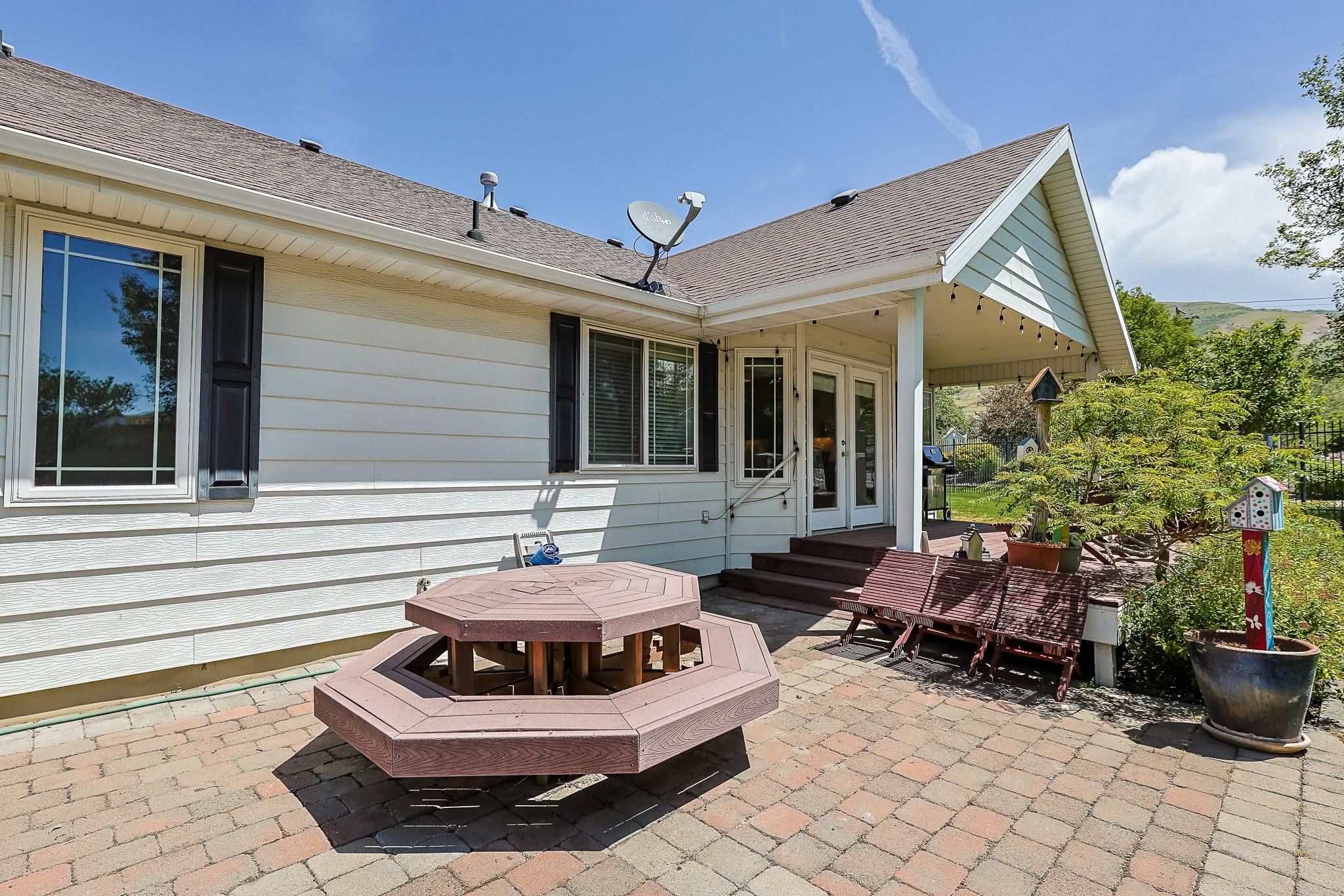Rear exterior featuring a brick paver patio, covered porch, and white siding