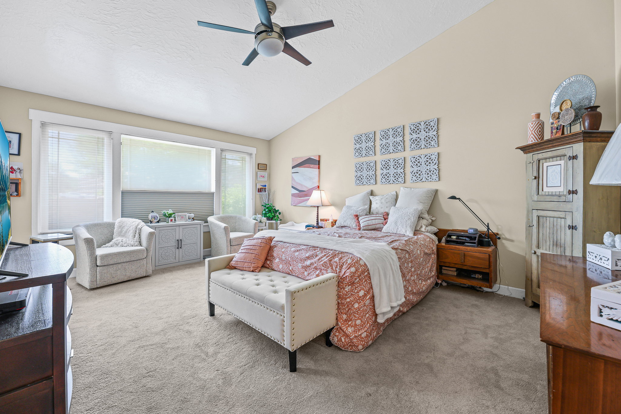 Carpeted room featuring a vaulted ceiling with a ceiling fan, a large window array with blinds, and white trim throughout