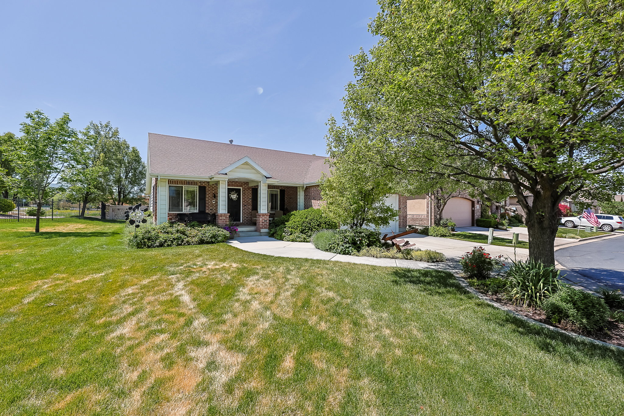 Traditional-style residence featuring a prominent front porch with white columns, dark shutters, and a brick facade accent